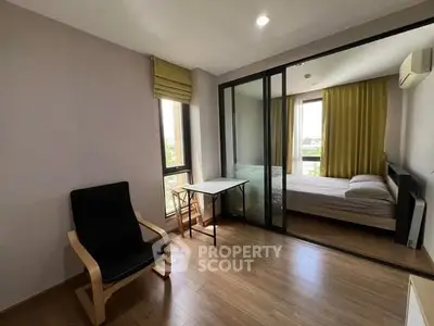Modern apartment with cozy bedroom and stylish living area, featuring large windows and sleek furnishings.