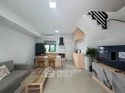 Modern open-plan living room with sleek kitchen and stylish staircase