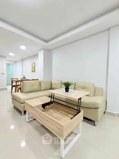 Modern living room with beige sectional sofa and innovative lift-top coffee table in a bright, open space.