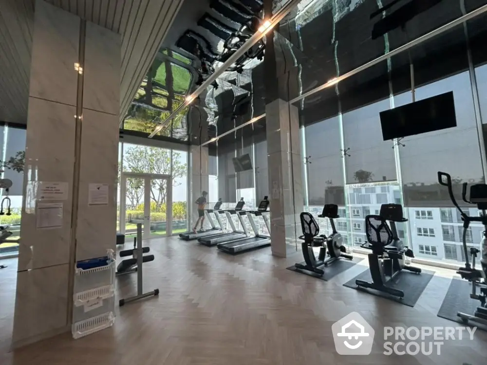 Luxurious gym with modern equipment and floor-to-ceiling windows offering stunning views.