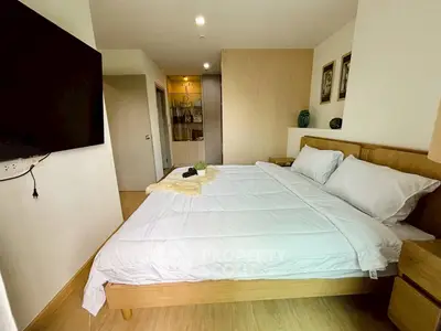 Modern bedroom with cozy wooden bed and large TV, perfect for relaxation.