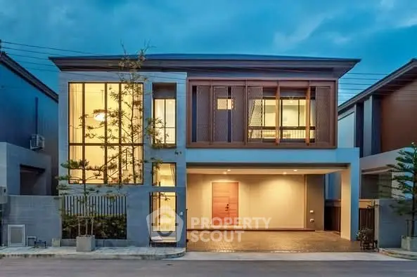 Modern two-story house with large windows and stylish facade at dusk.