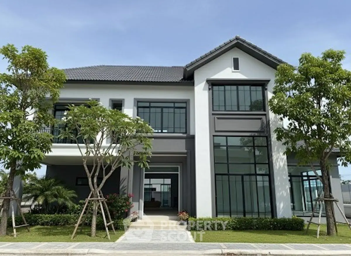 Modern two-story house with large windows and landscaped garden