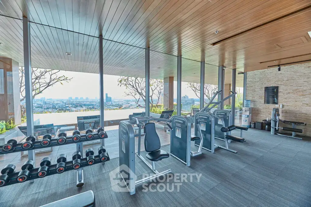 Luxurious gym with panoramic city views and modern fitness equipment in upscale residential building.