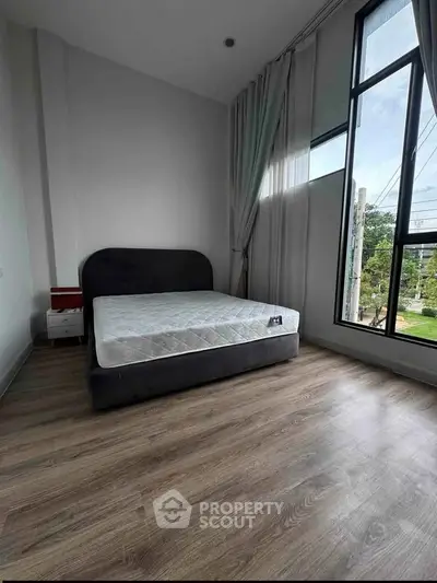 Spacious bedroom with large windows and modern decor in a stylish apartment.