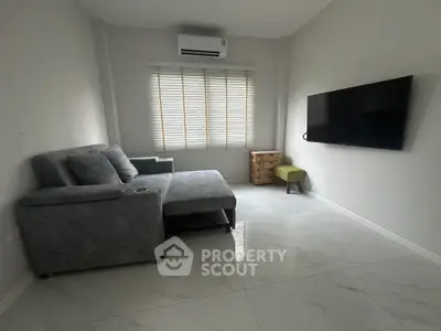 Modern living room with sleek gray sofa and wall-mounted TV in minimalist design.