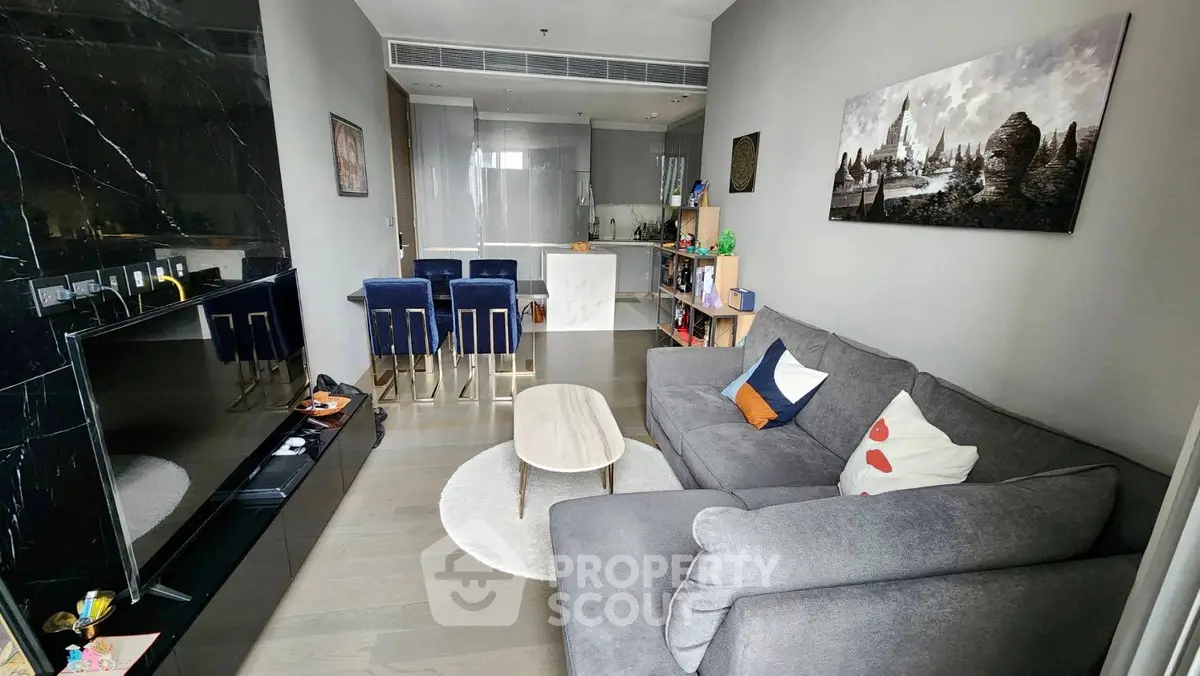 Modern living room with cozy gray sofa and stylish kitchen in open layout apartment.