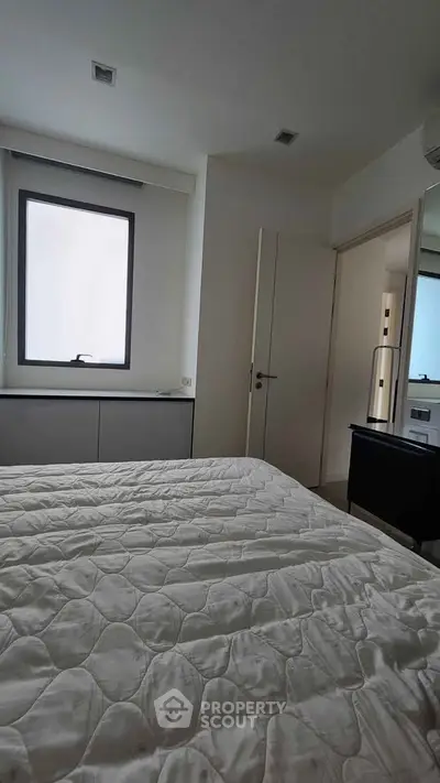 Cozy bedroom with large window and modern furnishings, perfect for relaxation and comfort.