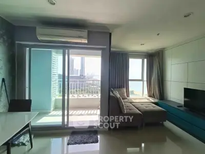 Modern living room with balcony and city view, featuring sleek furniture and ample natural light.