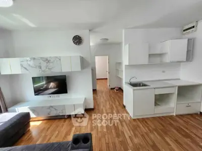 Modern living room with sleek wooden flooring and minimalist white cabinetry.