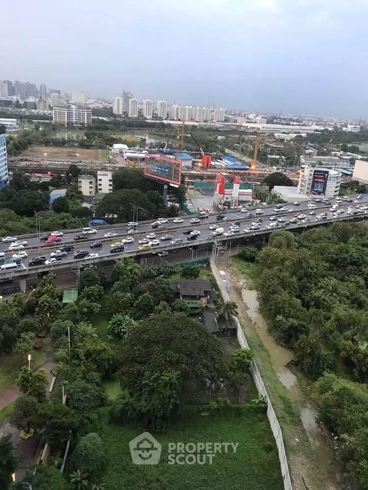 Stunning cityscape view from high-rise building overlooking lush greenery and bustling highway.