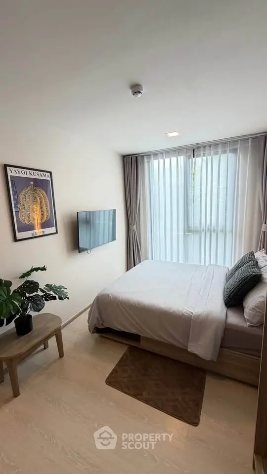 Modern bedroom with large window, wall-mounted TV, and stylish decor
