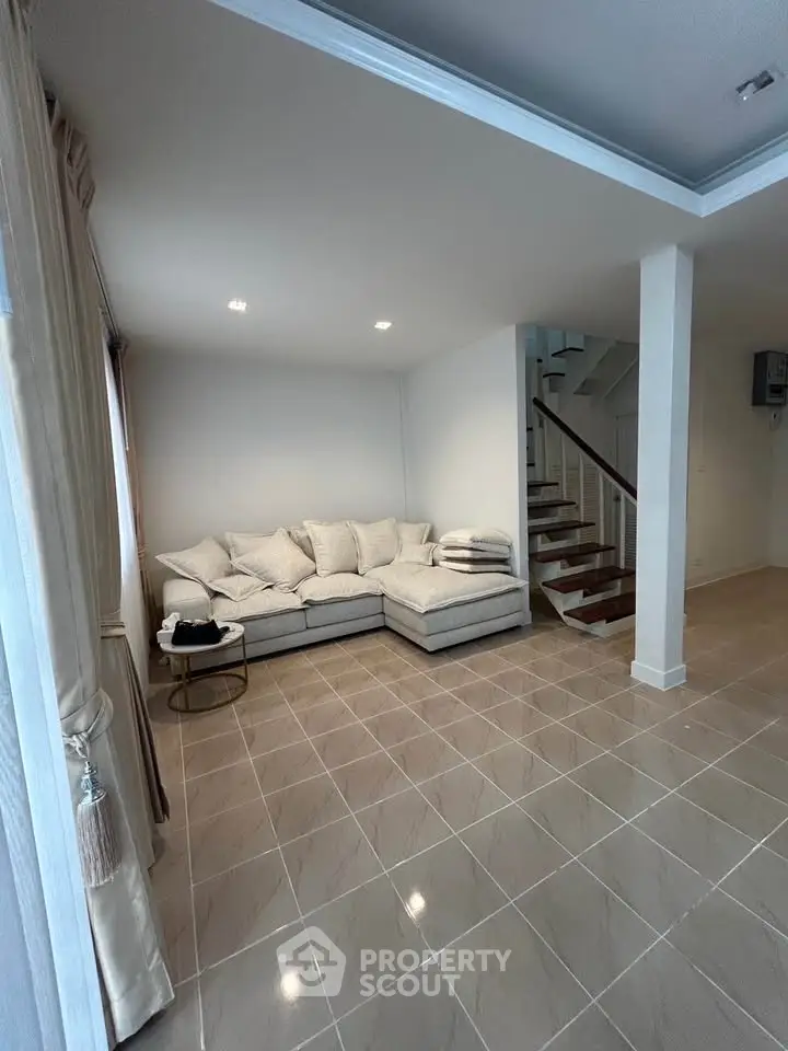Spacious living room with modern staircase and cozy corner sofa