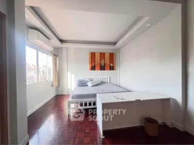 Spacious bedroom with modern decor and large window for natural light.