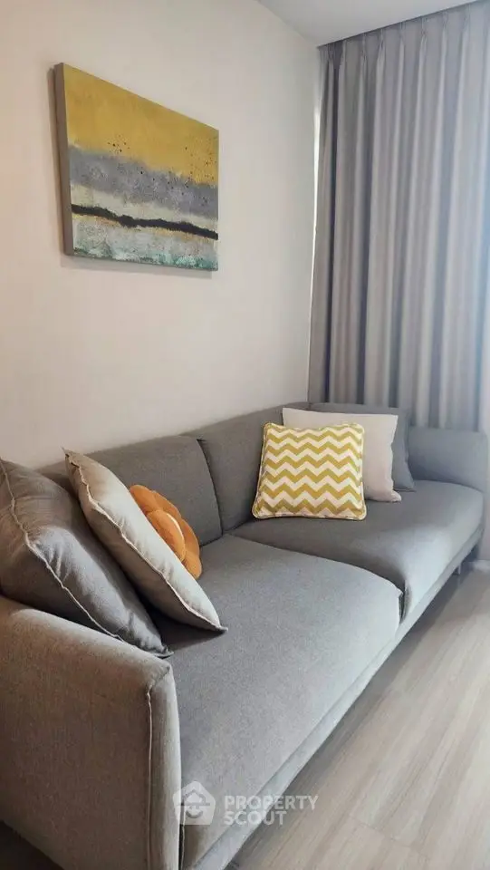 Modern living room with stylish gray sofa and abstract wall art