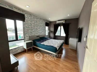 Modern bedroom with stylish wallpaper and wooden flooring, featuring a cozy bed and natural light.
