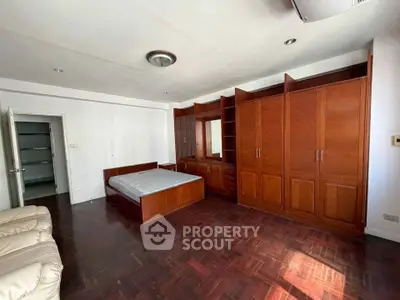 Spacious bedroom with wooden flooring and built-in wardrobe, featuring a cozy bed and ample natural light.
