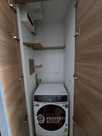 Compact laundry nook with modern washing machine and wooden shelving