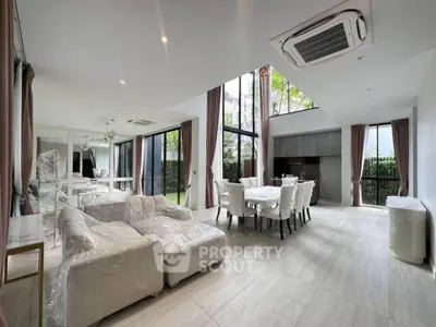 Spacious modern living and dining area with high ceilings and large windows offering natural light.