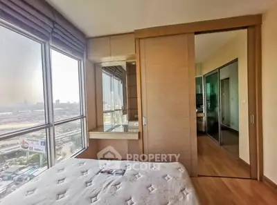 Modern bedroom with large windows offering stunning city views and ample natural light.