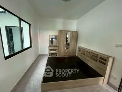 Spacious bedroom with modern wooden furniture and large window for natural light.