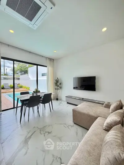 Modern living room with pool view, featuring sleek furniture and large windows for natural light.