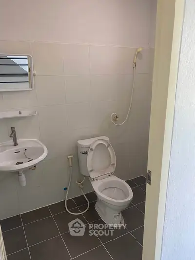 Compact bathroom with toilet, sink, and shower in modern apartment.