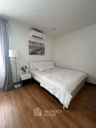 Modern bedroom with wooden flooring and air conditioning in a minimalist style apartment.