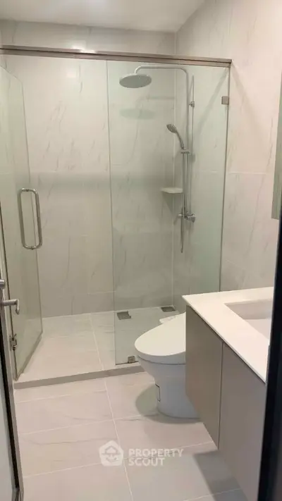 Modern bathroom with glass shower and sleek fixtures in contemporary apartment.