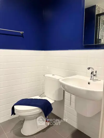 Modern bathroom with blue and white tiles, featuring a sleek sink and toilet.