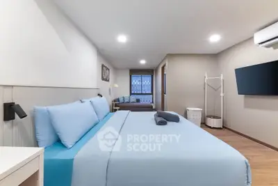 Spacious modern bedroom with blue bedding and wall-mounted TV