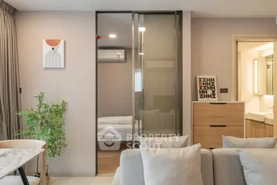 Modern living room with sliding glass doors leading to a cozy bedroom, featuring stylish decor and neutral tones.