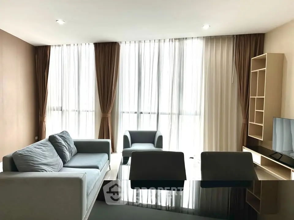 Modern living room with large windows, stylish furniture, and ample natural light.