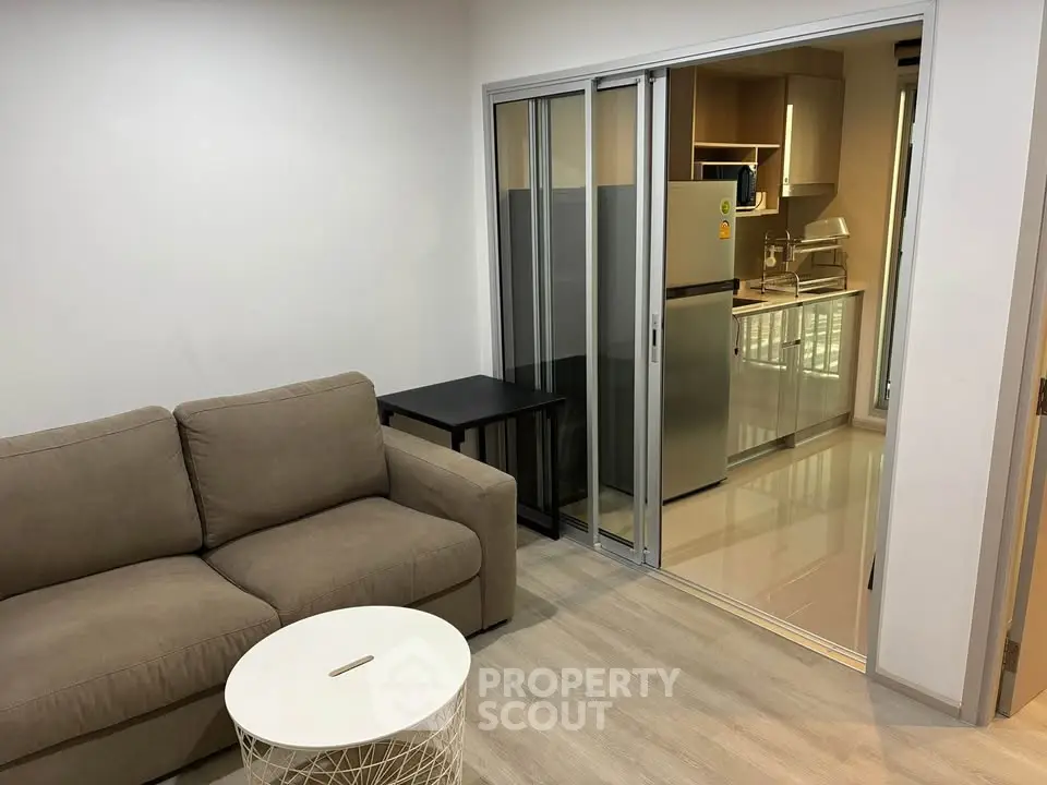 Modern living room with sliding glass doors leading to a sleek kitchen area.
