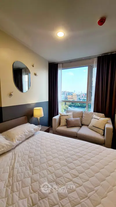 Cozy bedroom with city view, featuring a comfortable bed and stylish sofa.