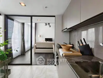 Modern open-layout kitchen with sleek design leading to a cozy living room with natural light.