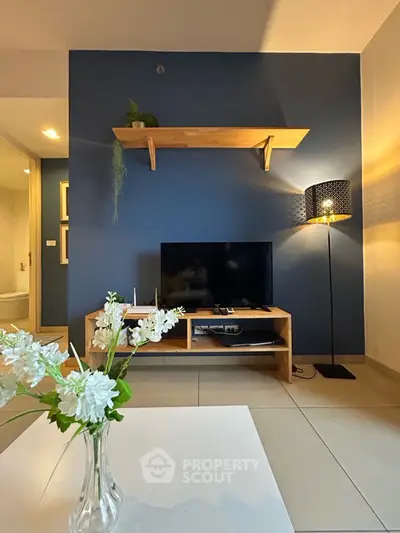 Modern living room with blue accent wall, stylish shelf, and cozy lighting.
