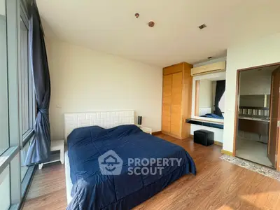 Spacious bedroom with modern decor and large windows for natural light.