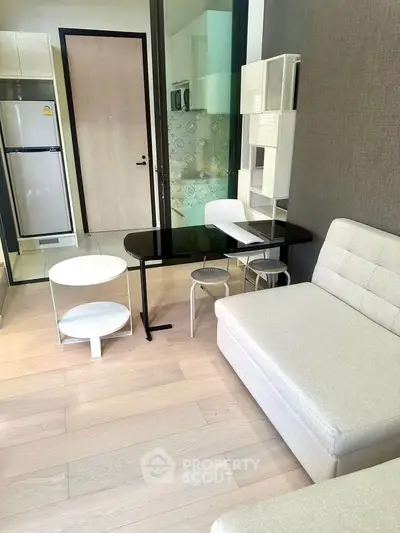 Modern living room with sleek furniture and open kitchen layout in a stylish apartment.