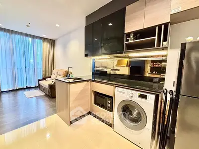 Modern open-layout kitchen with washing machine and cozy living area in a stylish apartment.