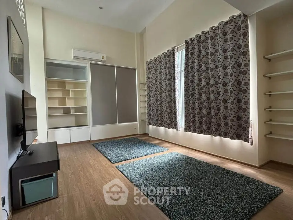 Spacious living room with modern shelving and large windows, perfect for natural light lovers.
