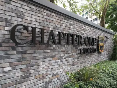 Elegant brick exterior of Chapter One Ladprao with lush greenery, showcasing modern urban living.