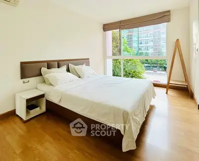 Spacious bedroom with large window and modern decor in a luxury apartment.