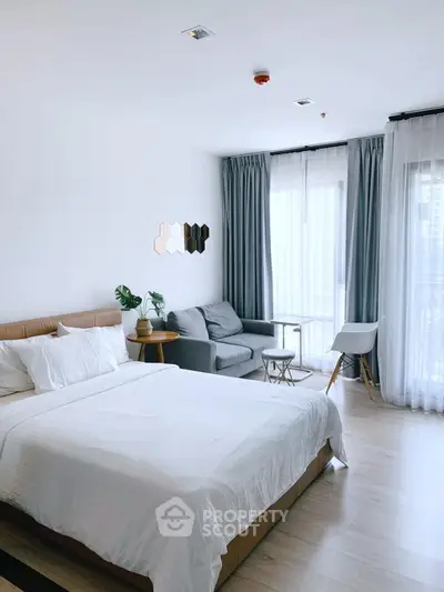 Spacious modern bedroom with cozy seating area and natural light