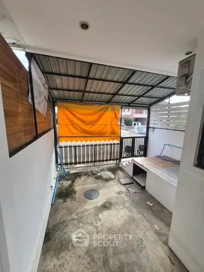 Covered outdoor area with orange tarp and concrete flooring