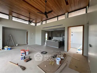 Spacious modern living room with high wooden ceiling and open kitchen layout.