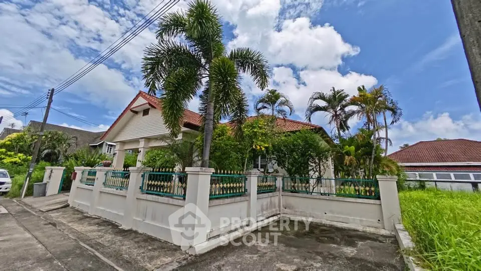 Charming suburban house with lush garden and red-tiled roof under a bright blue sky.