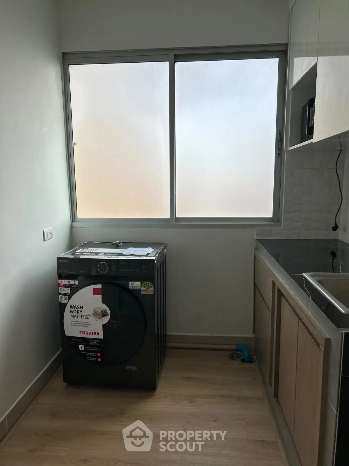 Modern laundry area with washing machine and sleek cabinetry in a bright, compact space.