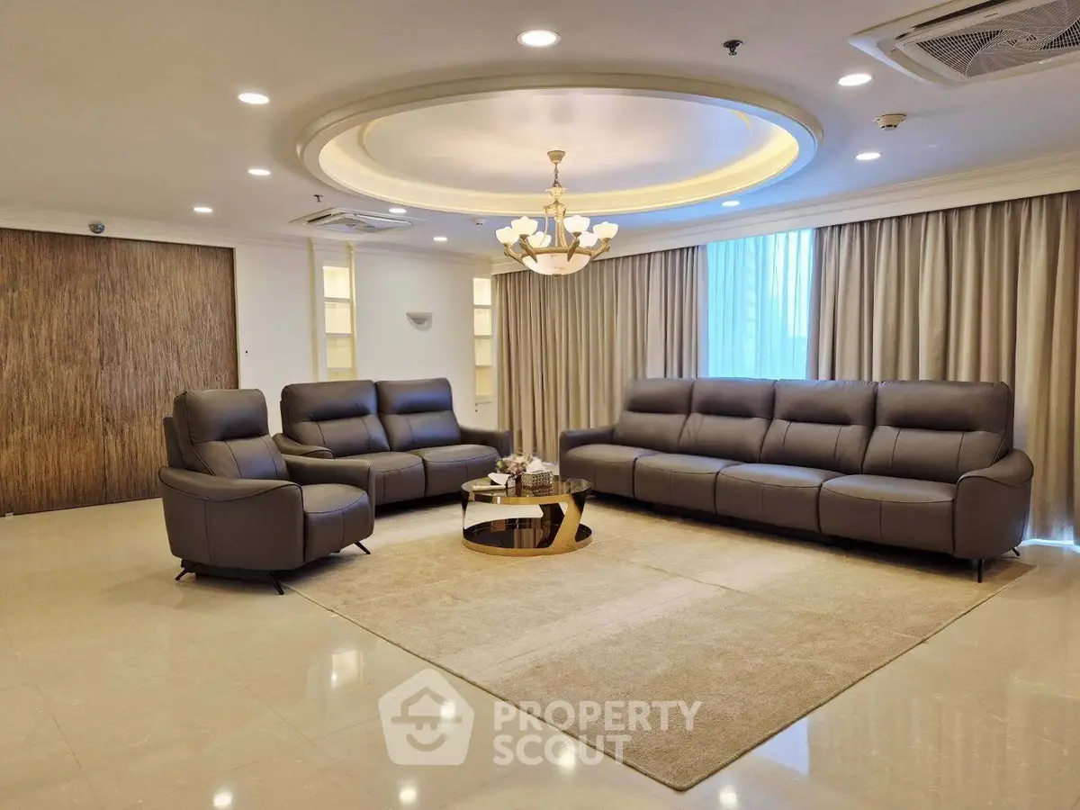 Luxurious living room with elegant leather sofas and modern chandelier in a spacious apartment.