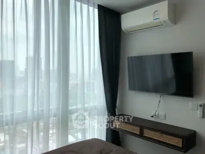 Modern bedroom with large window, wall-mounted TV, and air conditioning unit in a high-rise apartment.